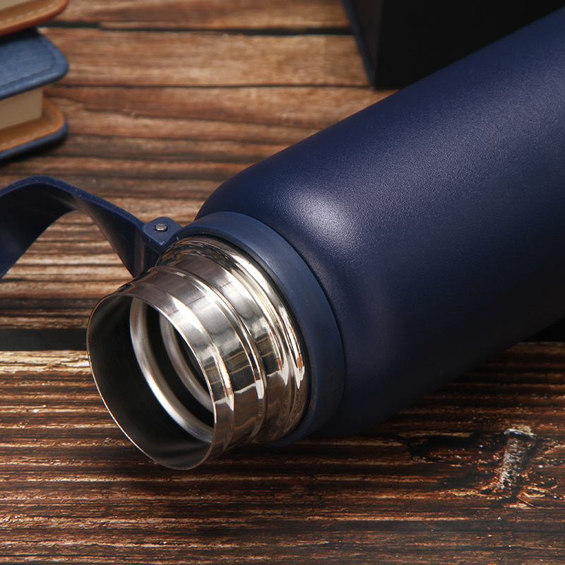 a black stainless steel water bottle on the wood table